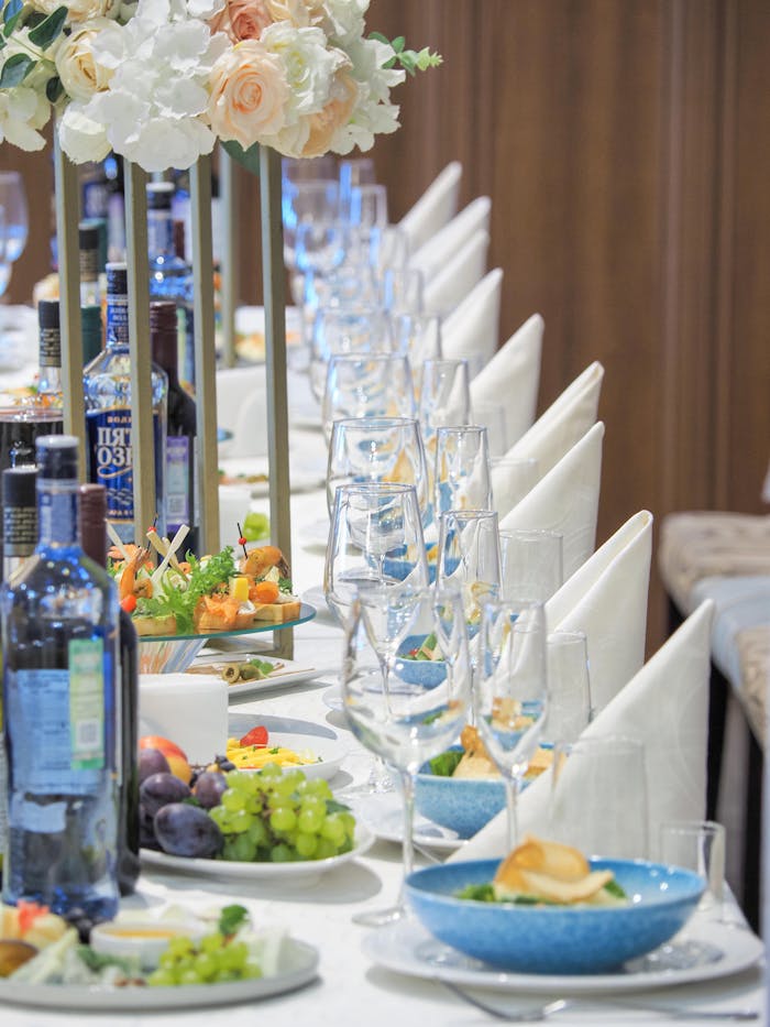 Beautiful table setup with glassware, elegant flowers, and an assortment of food and wine.