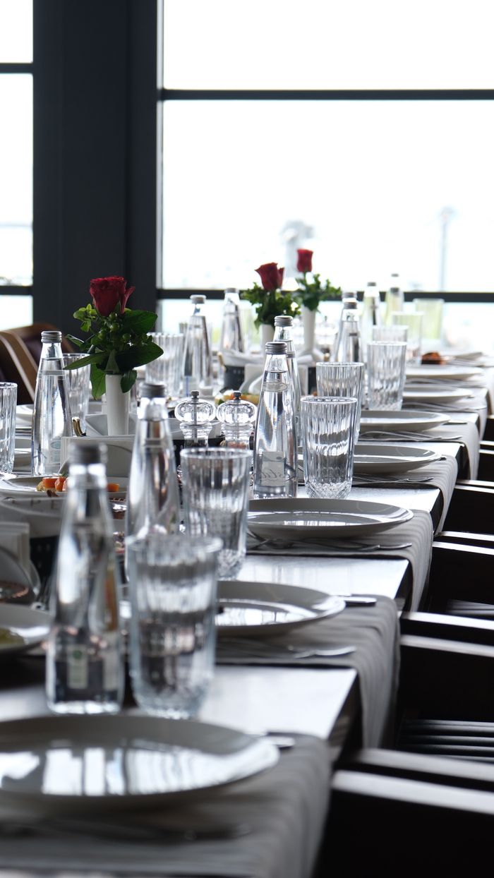 Chic table setup with glassware and red roses in a modern restaurant.