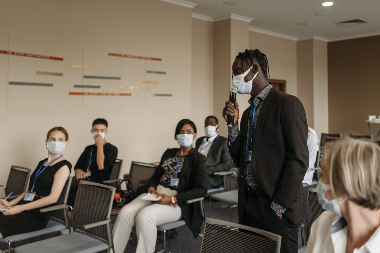 Business seminar with participants wearing face masks, actively engaging in a discussion.